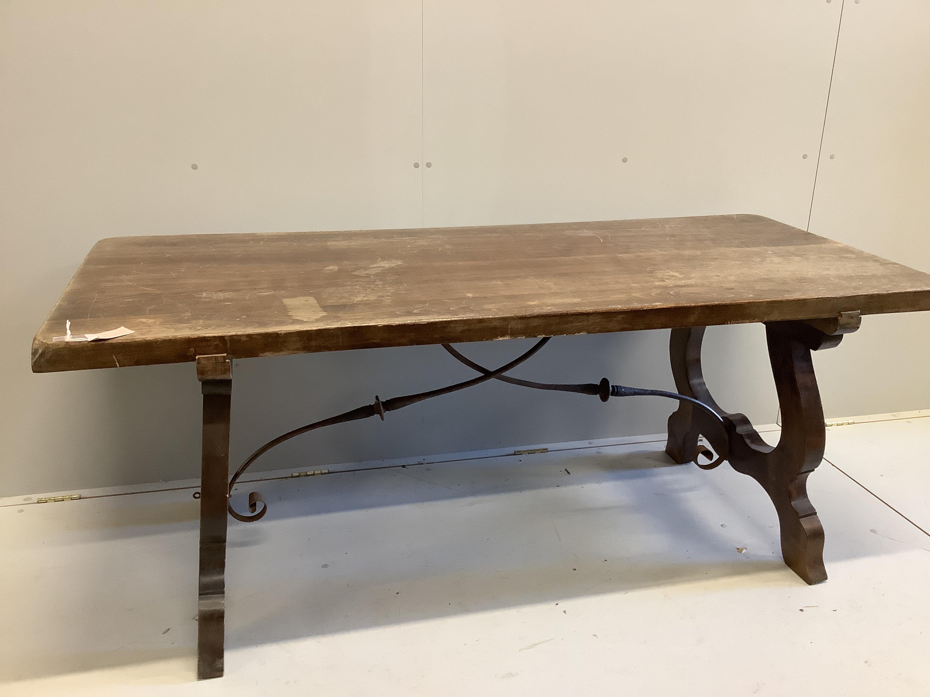 A Spanish style beech rectangular dining table, on shaped supports with iron stretcher, length 180cm, width 78cm, height 74cm